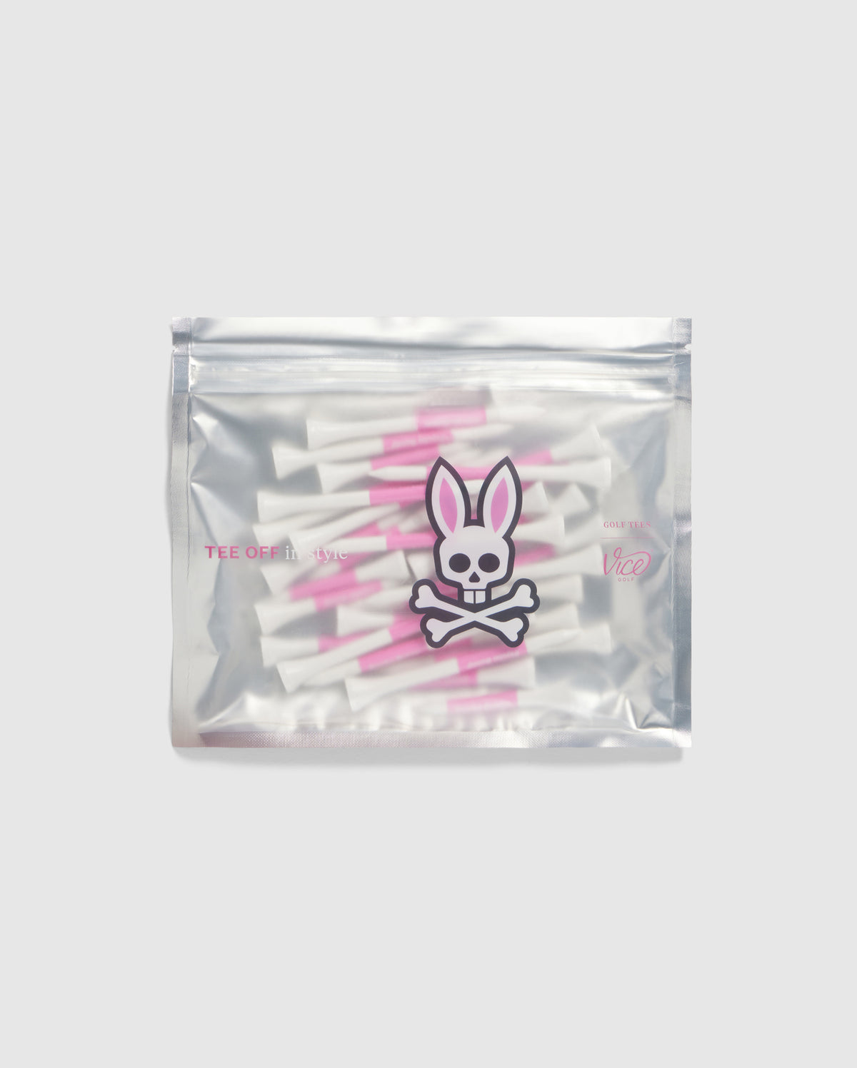 A silver pouch adorned with the Psycho Bunny logo, featuring a bunny skull and crossbones, houses the brand's 75 Pack Golf Tees in white and pink. Set against a simple gray backdrop, these Bamboo golf accessories are sure to capture attention with their distinctive charm and uniqueness.