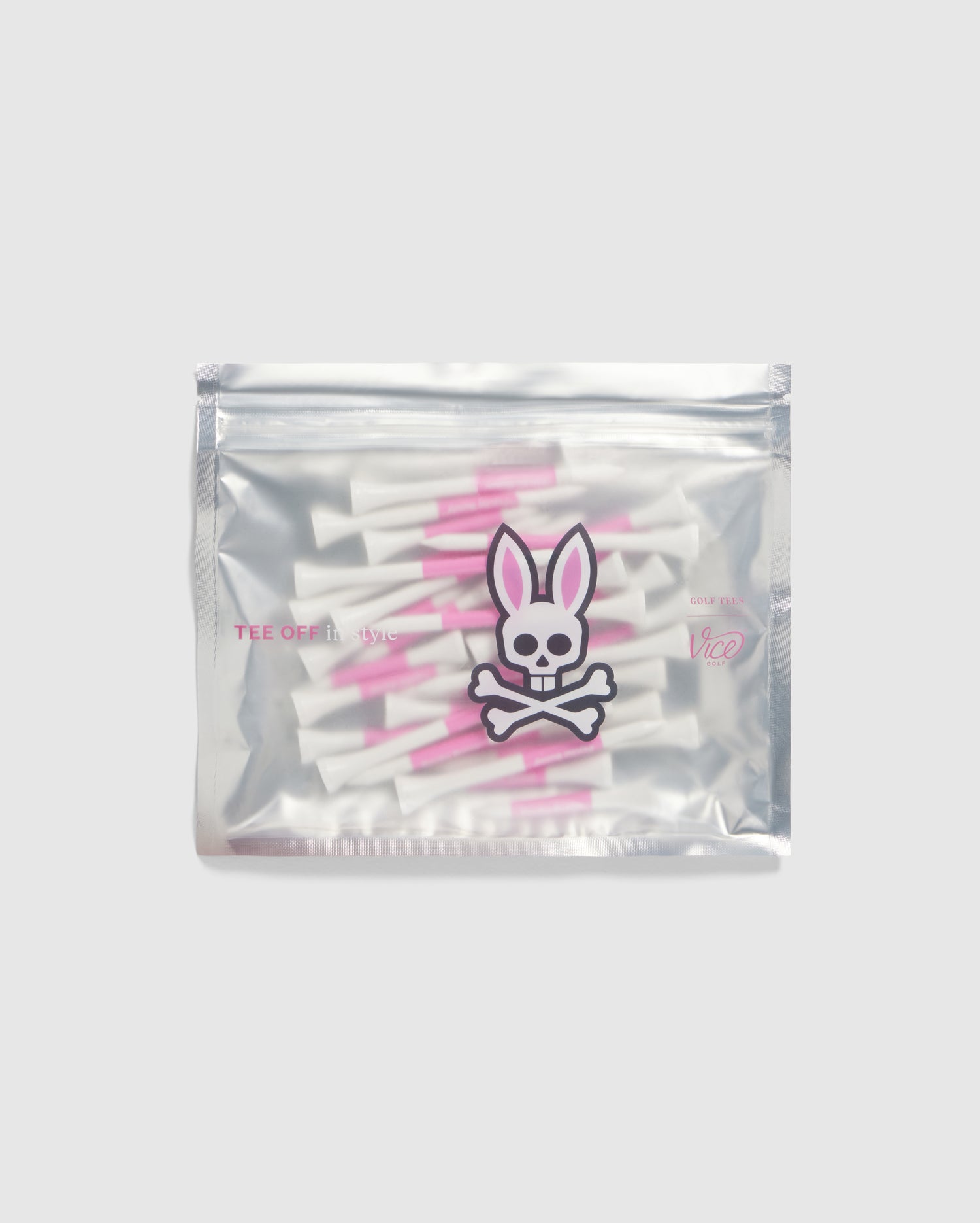 A silver pouch adorned with the Psycho Bunny logo, featuring a bunny skull and crossbones, houses the brand's 75 Pack Golf Tees in white and pink. Set against a simple gray backdrop, these Bamboo golf accessories are sure to capture attention with their distinctive charm and uniqueness.