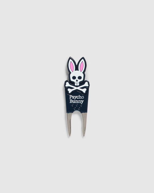 Image of a DIVOT TOOL - B6A699C200 from Psycho Bunny with a design featuring a skull with bunny ears and the text "Psycho Bunny" underneath. The tool has two prongs at the bottom, and the skull and ears are in black, white, and pink. A perfect addition to golf gifts, this tool also comes with a magnetic ball marker. The background is plain gray.