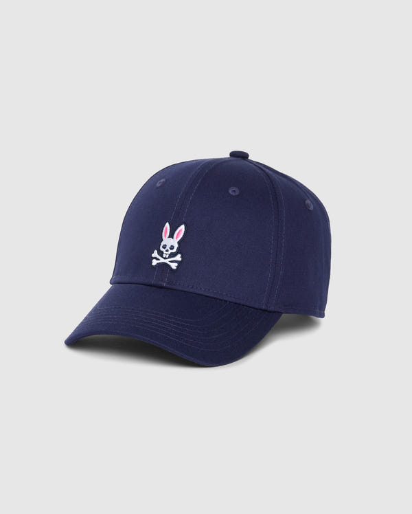 The Psycho Bunny Men's Classic Baseball Cap - B6A816A1HT is a timeless navy blue accessory featuring an embroidered bunny skull with crossbones in white and pink on the front. Crafted from 100% cotton, this classic cap has six panels, ventilation eyelets, and a curved brim. The background color of the description is light gray.