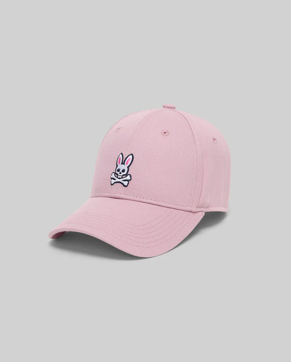 The Psycho Bunny MENS CLASSIC BASEBALL CAP - B6A816A1HT in light pink features an embroidered Bunny with crossbones on the front and an adjustable fit, displayed against a plain gray background.