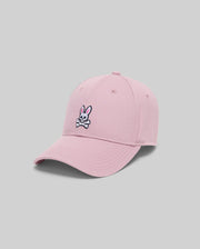 The Psycho Bunny MENS CLASSIC BASEBALL CAP - B6A816A1HT in light pink features an embroidered Bunny with crossbones on the front and an adjustable fit, displayed against a plain gray background.