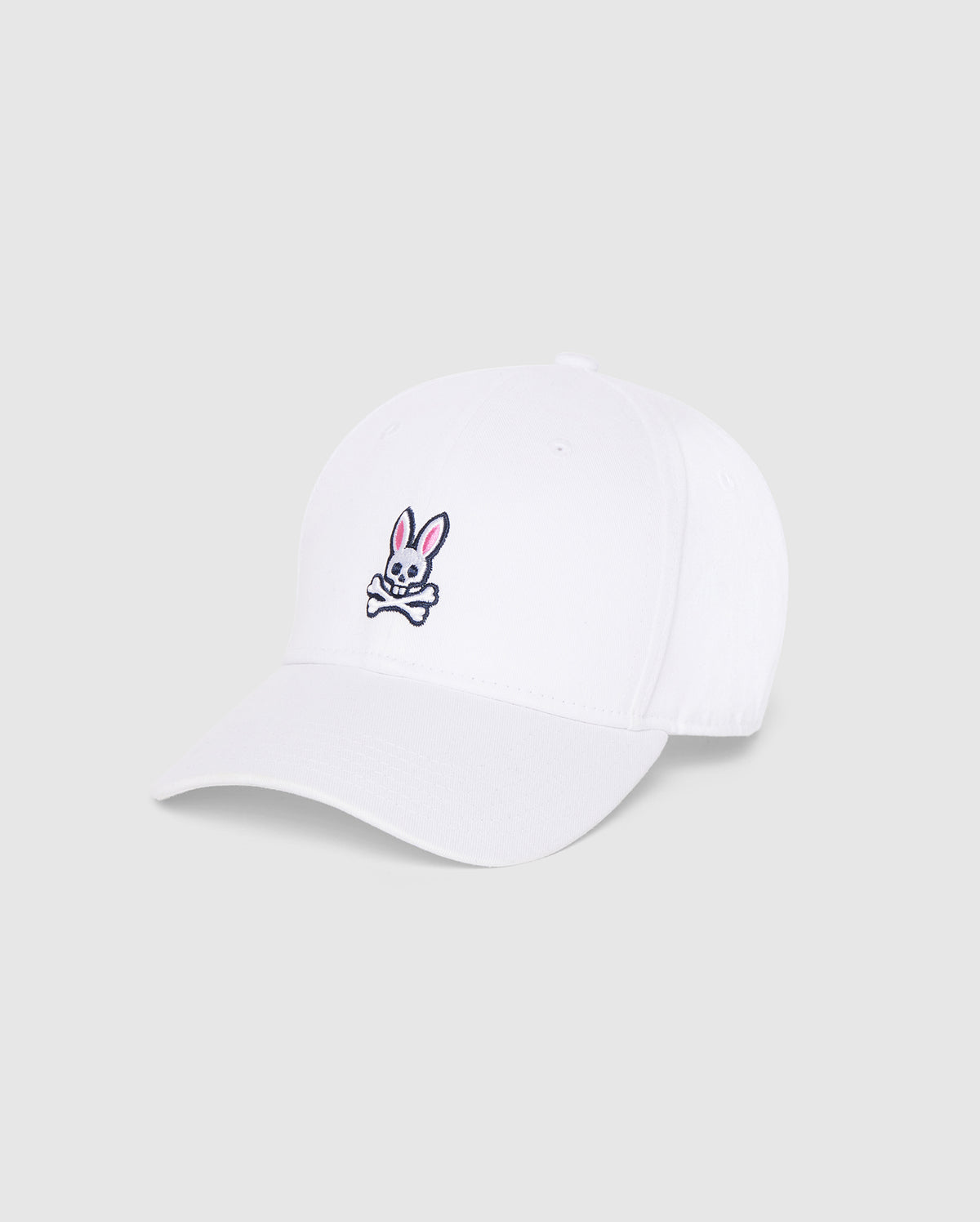 A MENS CLASSIC BASEBALL CAP - B6A816A1HT made from durable cotton twill, featuring a small embroidered logo on the front. The playful design showcases a pink and white bunny head above crossed bones to create a unique skull and crossbones motif. It comes with a curved brim and an adjustable backstrap. This cap is from Psycho Bunny.