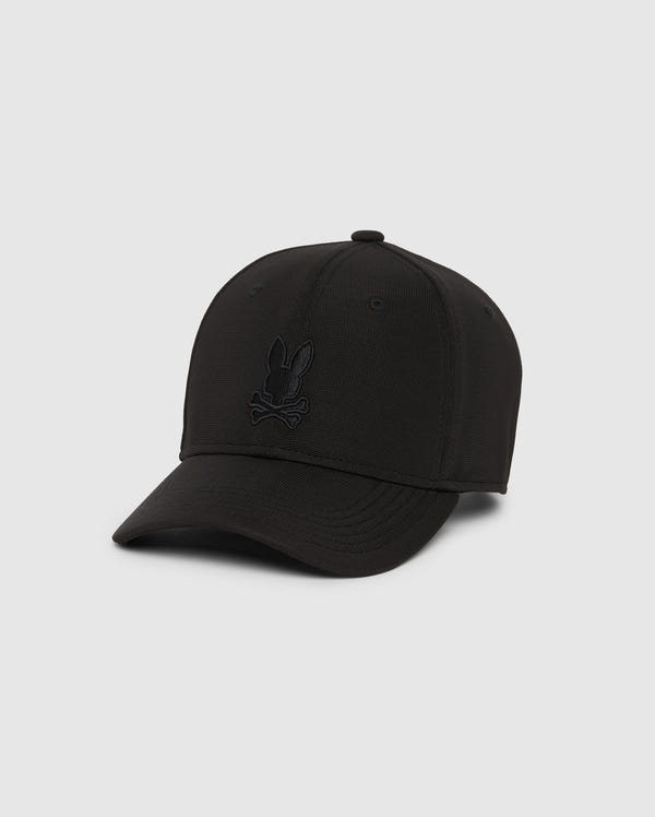 The Psycho Bunny Men's James Premium Baseball Cap (B6A953D200) showcases an embroidered Bunny head with crossbones on the front, crafted from a high-quality blend of polyester and spandex. It has a curved brim and six-panel construction, set against a simple light gray background for an understated yet fashionable appeal.