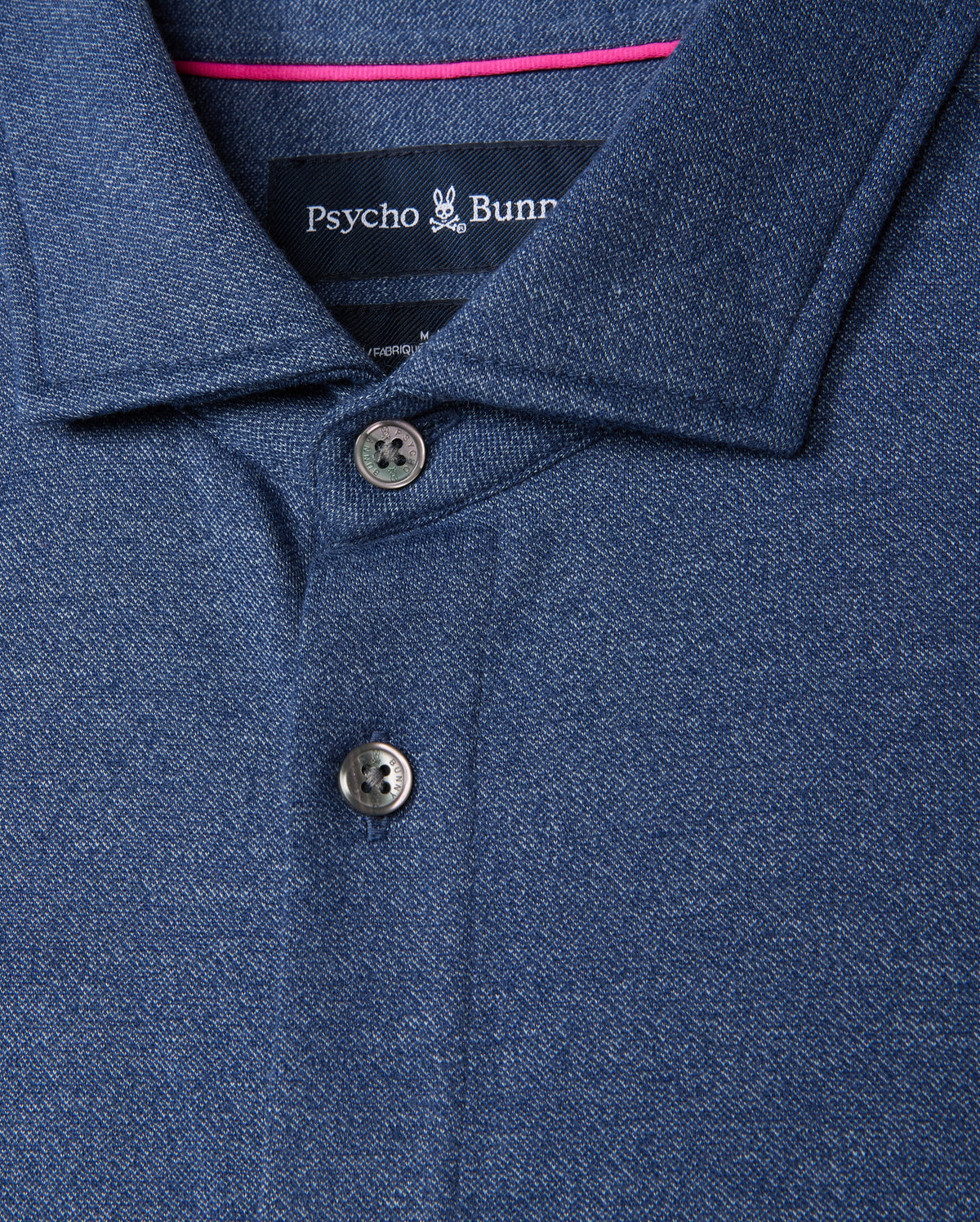 Close-up of a Psycho Bunny Men's Dalton Knit Shirt - B6C747D200 in dark blue, made from luxurious Peruvian Pima cotton. It features a collar with two buttons and a subtle textured pattern for an elegant knit shirt feel. The brand label is sewn inside beneath the collar.