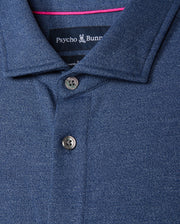 Close-up of a Psycho Bunny Men's Dalton Knit Shirt - B6C747D200 in dark blue, made from luxurious Peruvian Pima cotton. It features a collar with two buttons and a subtle textured pattern for an elegant knit shirt feel. The brand label is sewn inside beneath the collar.