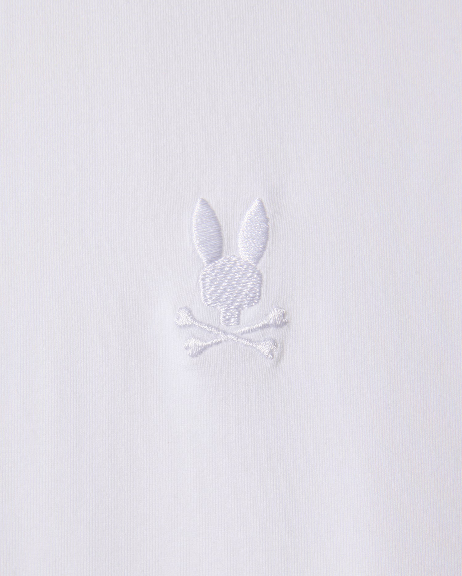 The MENS ARTHUR JERSEY SHIRT - B6C748D200 by Psycho Bunny is made from white jersey fabric and features a discreet embroidered design of a bunny head atop two crossed bones.