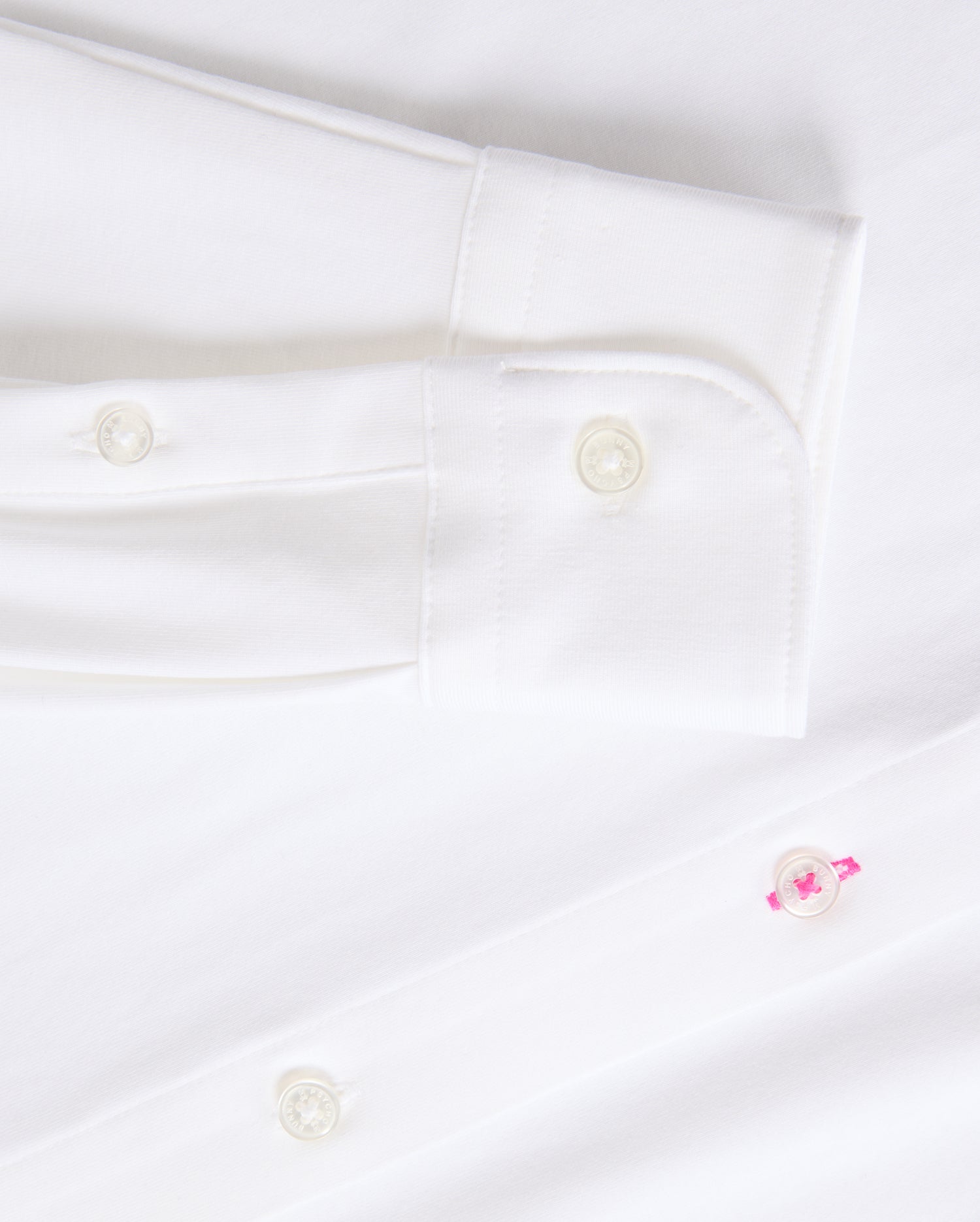 Get a closer look at the timeless MENS ARTHUR JERSEY SHIRT - B6C748D200 from Psycho Bunny, made from smooth stretch Pima cotton. It showcases a sleeve cuff with two white buttons and a distinctive pink button on the shirt front.
