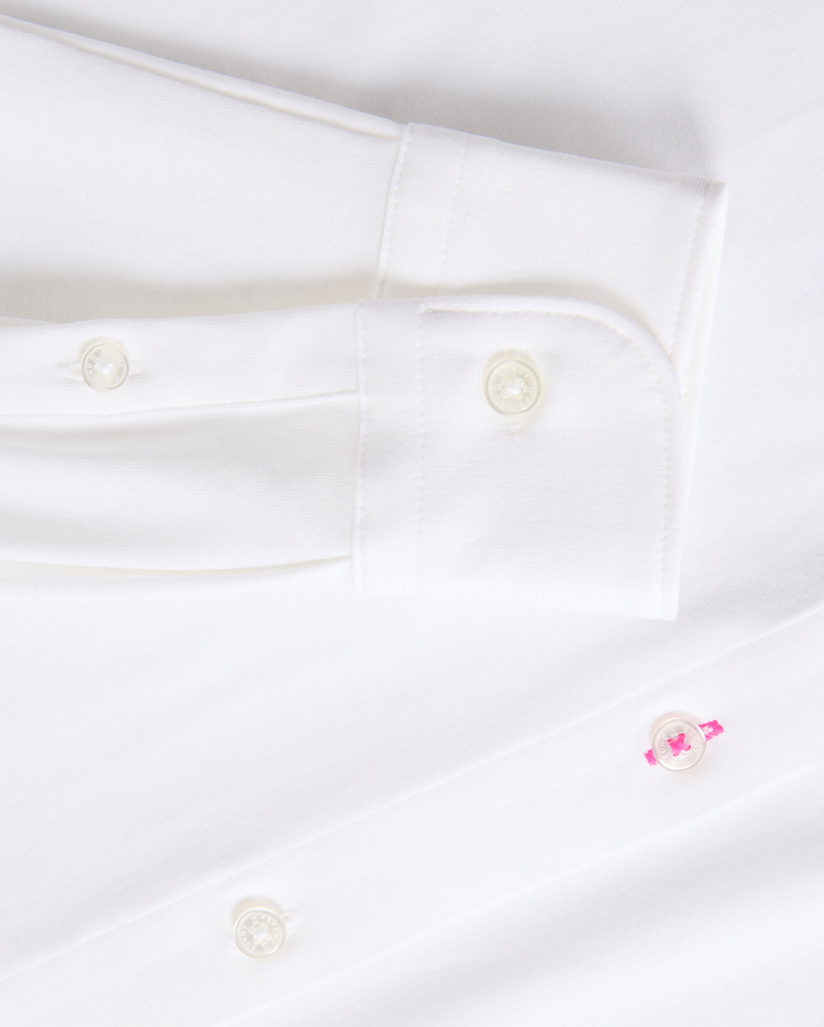 Get a closer look at the timeless MENS ARTHUR JERSEY SHIRT - B6C748D200 from Psycho Bunny, made from smooth stretch Pima cotton. It showcases a sleeve cuff with two white buttons and a distinctive pink button on the shirt front.