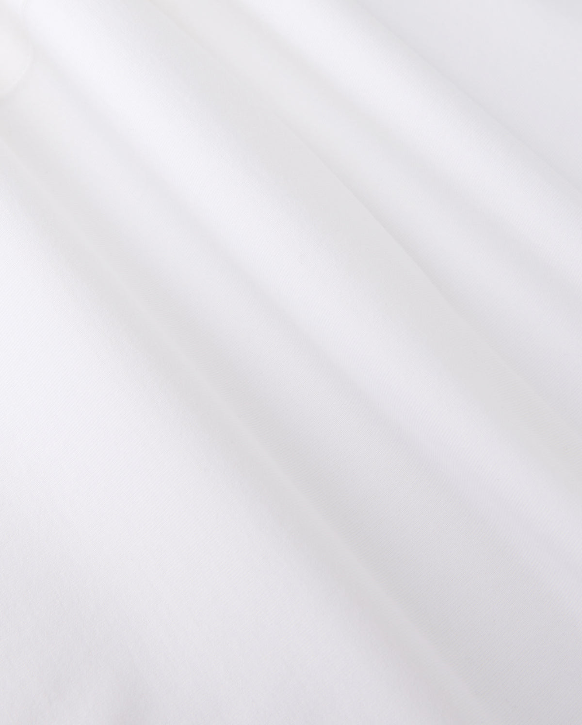 Close-up of smooth, white jersey fabric with gentle shadows forming soft folds. The texture appears soft and slightly matte, reminiscent of the MENS ARTHUR JERSEY SHIRT - B6C748D200 by Psycho Bunny, evoking a sense of lightness and simplicity.