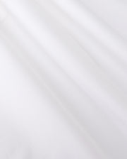 Close-up of smooth, white jersey fabric with gentle shadows forming soft folds. The texture appears soft and slightly matte, reminiscent of the MENS ARTHUR JERSEY SHIRT - B6C748D200 by Psycho Bunny, evoking a sense of lightness and simplicity.