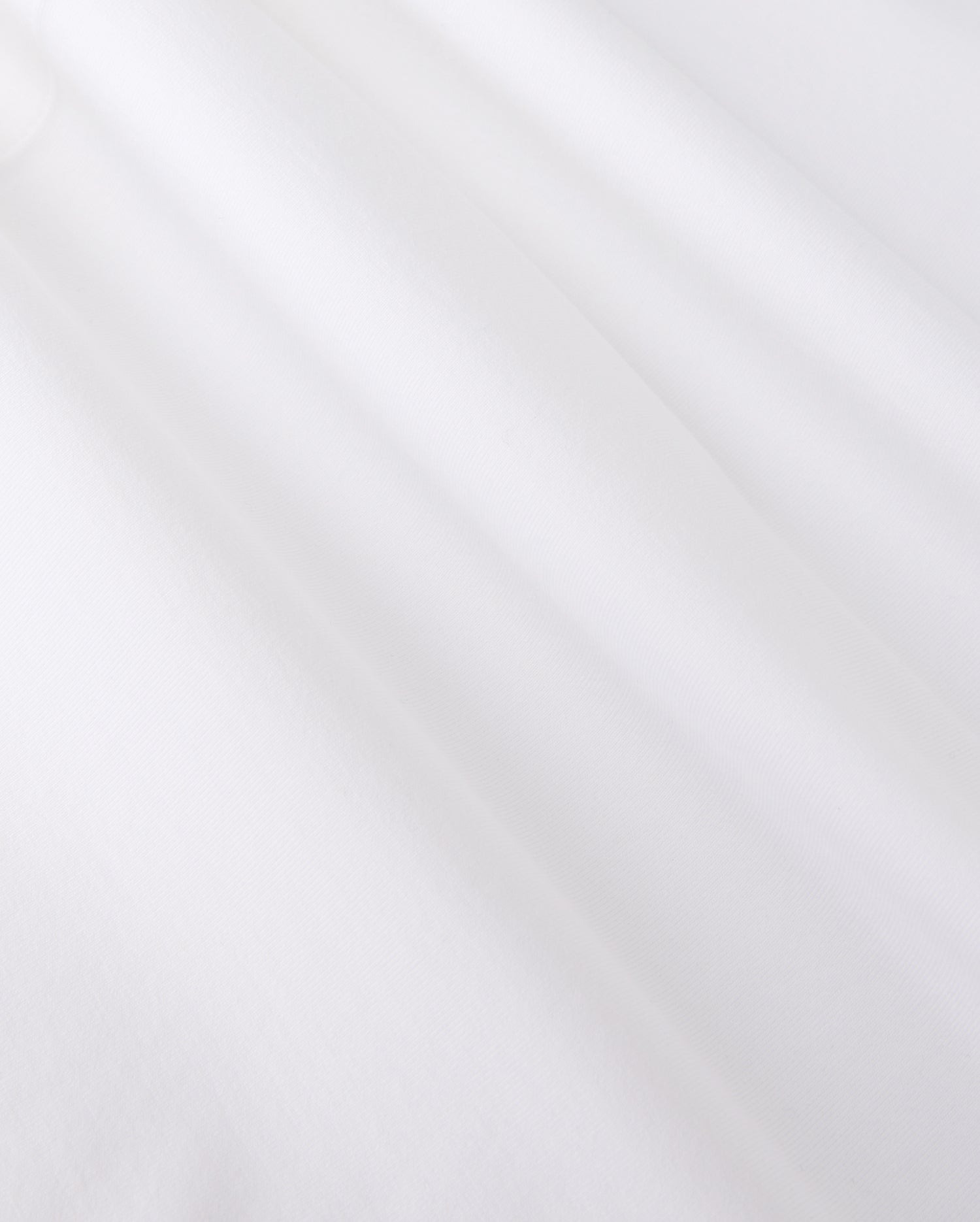 Close-up of smooth, white jersey fabric with gentle shadows forming soft folds. The texture appears soft and slightly matte, reminiscent of the MENS ARTHUR JERSEY SHIRT - B6C748D200 by Psycho Bunny, evoking a sense of lightness and simplicity.