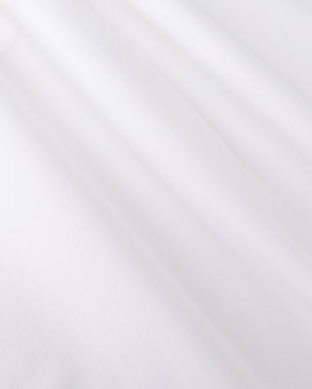 Close-up of smooth, white jersey fabric with gentle shadows forming soft folds. The texture appears soft and slightly matte, reminiscent of the MENS ARTHUR JERSEY SHIRT - B6C748D200 by Psycho Bunny, evoking a sense of lightness and simplicity.
