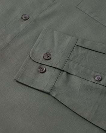 Close-up of a green fabric with a flap pocket and four black buttons from the Psycho Bunny MENS JARED COTTON MODAL SHIRT. The premium cotton modal fabric appears smooth and neatly stitched, showcasing a visible part of this men's garment.