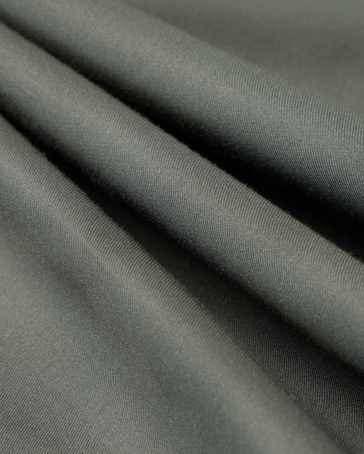Close-up of the olive green fabric from the Psycho Bunny MENS JARED COTTON MODAL SHIRT - B6C774D200, showcasing its smooth texture and flowing drapes reminiscent of a premium shirt.
