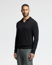 A man with a short beard poses against a plain white background, sporting the MENS JOHNNY COLLAR SWEATER - B6E258E200 by Psycho Bunny. The sleek black sweater, crafted from a comfortable cotton-wool blend, is paired with gray pants as he rests his hands by his sides.