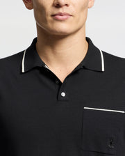 A person is wearing a Psycho Bunny Men's Longford Fine Knit Polo (B6E500F200), featuring an embroidered Bunny on the pocket, with white trim on the collar and pocket edge, all set against a plain white background.