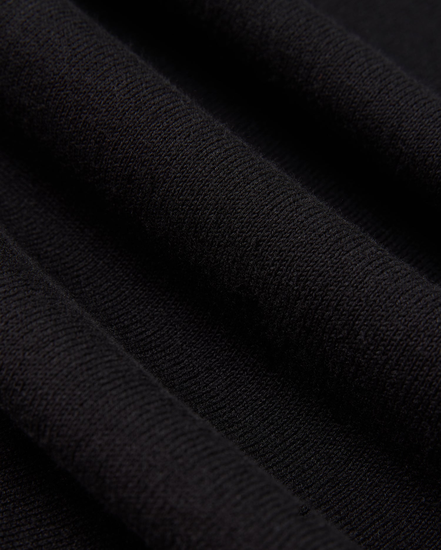 A detailed view of the Psycho Bunny MENS BELMORE EXTRA FINE COTTON SWEATER - B6E832D200 showcases the intricate ribbed texture formed by parallel lines in its extrafine cotton knit. The lighting accentuates the sweater's high-quality stitching, enhancing its soft and luxurious look.