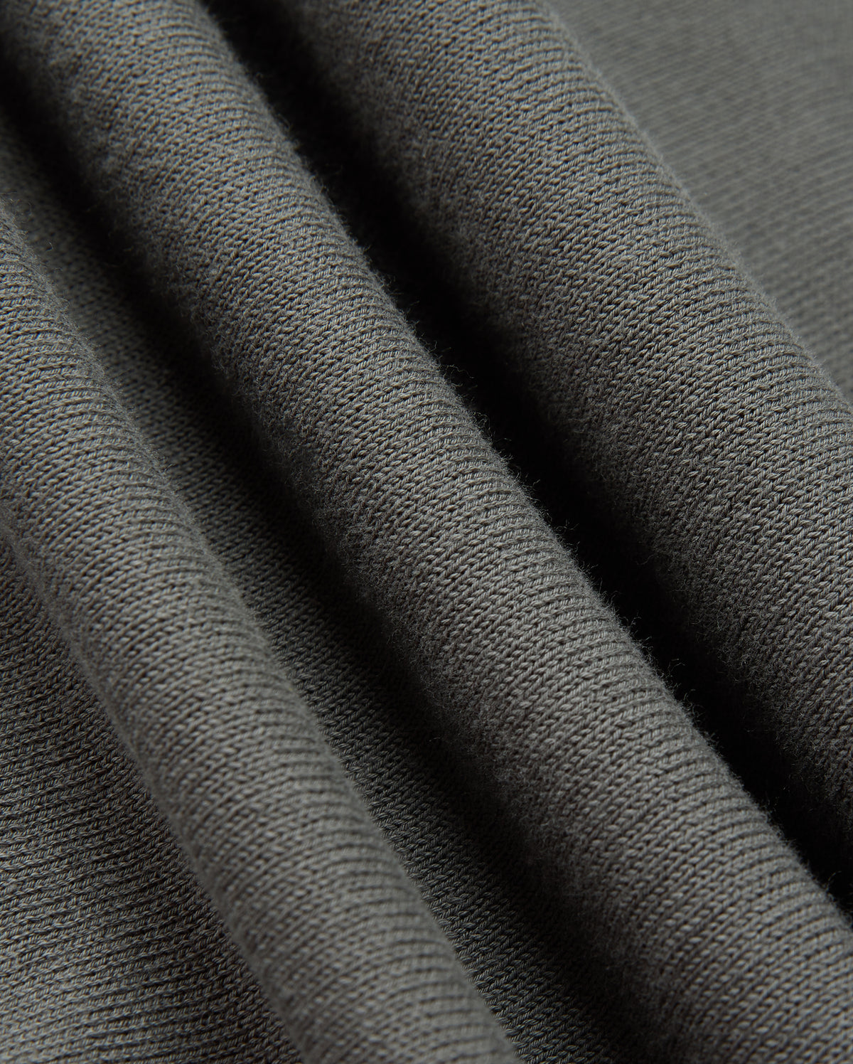 Close-up of the Psycho Bunny MENS BELMORE COTTON SWEATER - B6E832D200 in dark gray, highlighting its exquisite textured surface. The material exudes a soft and cozy feel, with delicate parallel lines that reveal the knit pattern and fabric thickness, capturing the luxurious essence of premium cotton craftsmanship.