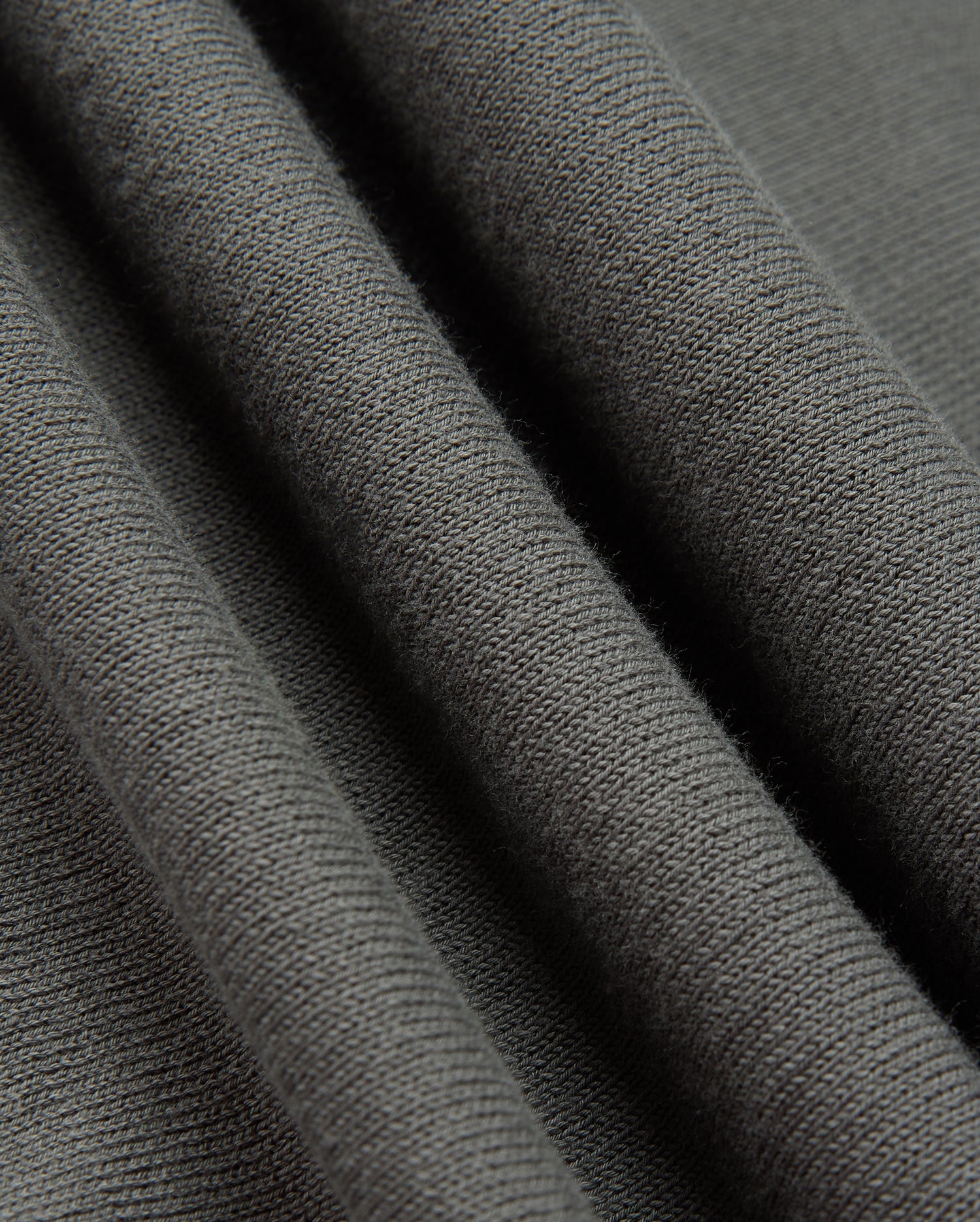 Close-up of the Psycho Bunny MENS BELMORE COTTON SWEATER - B6E832D200 in dark gray, highlighting its exquisite textured surface. The material exudes a soft and cozy feel, with delicate parallel lines that reveal the knit pattern and fabric thickness, capturing the luxurious essence of premium cotton craftsmanship.
