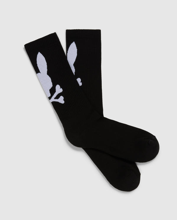 The Psycho Bunny MENS 3 PACK SPORT SOCK - B6F997D200 includes three pairs of black knee-high sport socks made from luxurious Peruvian pima cotton. These socks feature a distinctive white design that showcases a stylized skull and crossbones, with the skull cleverly shaped like a rabbit head. The socks are carefully arranged side by side on a simple gray background.