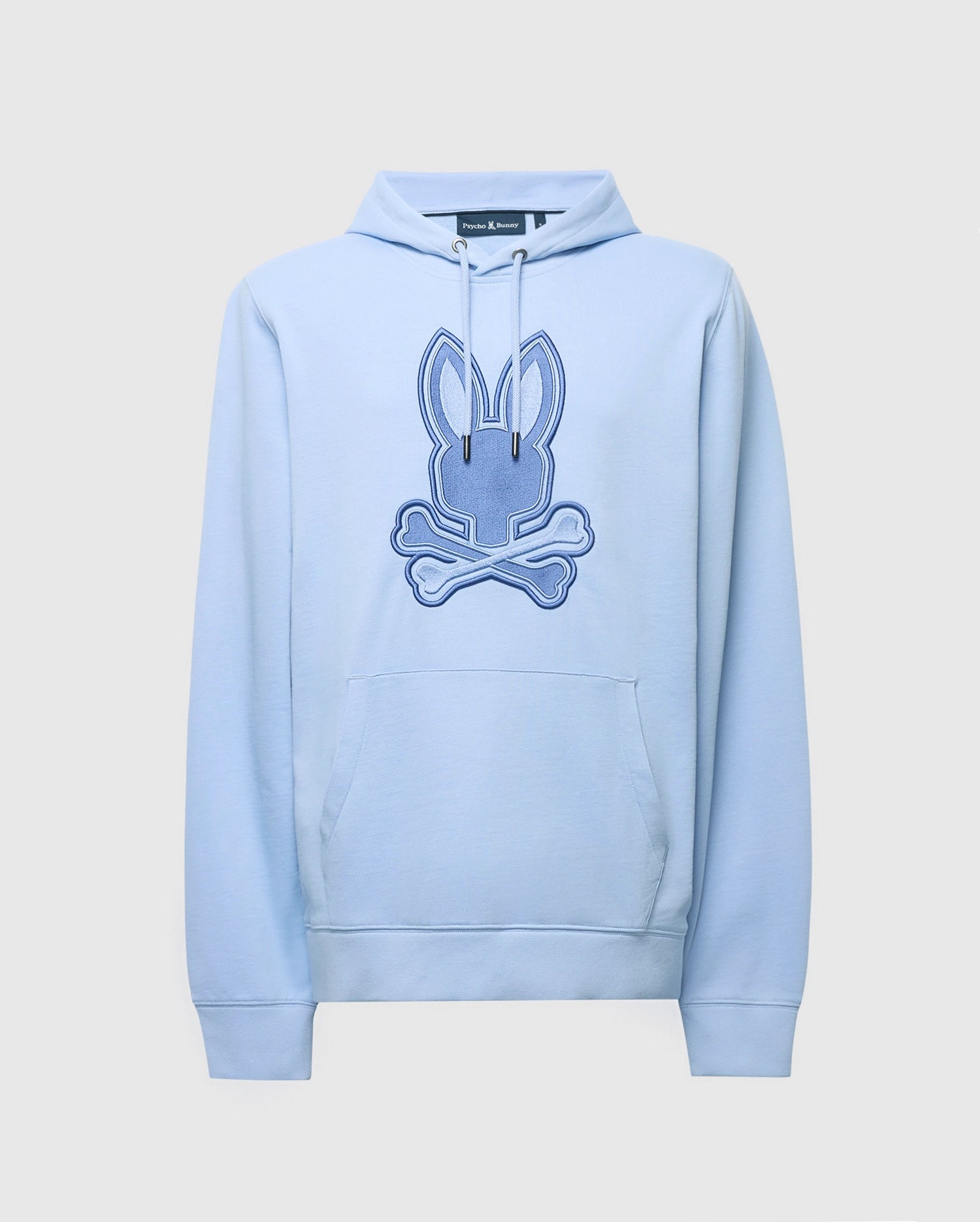 Psycho Bunny's Men's New Castle Hoodie (B6H517F200) is light blue, made from soft French terry fabric, and features an embroidered bunny head with crossbones at the center. It includes a front pocket and drawstring hood.