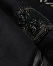 Close-up of the Psycho Bunny MENS BRAYDEN WOOL LEATHER VARSITY BOMBER - B6J876D200, showcasing an embroidered design with overlapping bones and intricate stitching. The thick, textured wool-blend fabric highlights the detailed craftsmanship of this black varsity jacket.