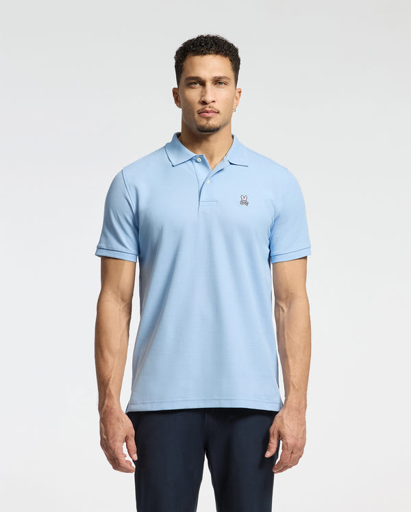 A person wearing the MENS CLASSIC PIQUE POLO SHIRT - B6K001B200 from Psycho Bunny, crafted from soft Pima cotton and featuring a small embroidered Bunny logo on the chest, stands against a plain background.