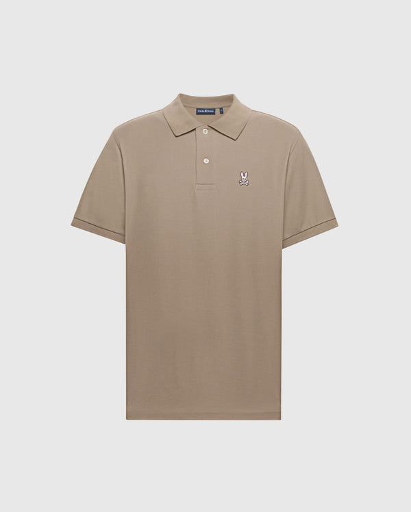 The Men's Classic Pique Polo Shirt - B6K001CRPC by Psycho Bunny is a light brown Pima cotton polo shirt with short sleeves. It features a small embroidered rabbit head with pink ears on the left chest, a classic collar, and a two-button placket.