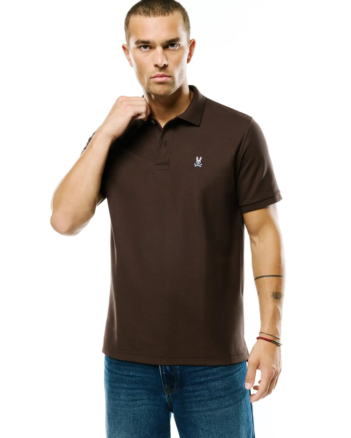 Men's Classic Pima Pique Polo in rich brown pique fabric, featuring a small, embroidered white Psycho Bunny skull logo on the left chest, with a classic fit. (2)