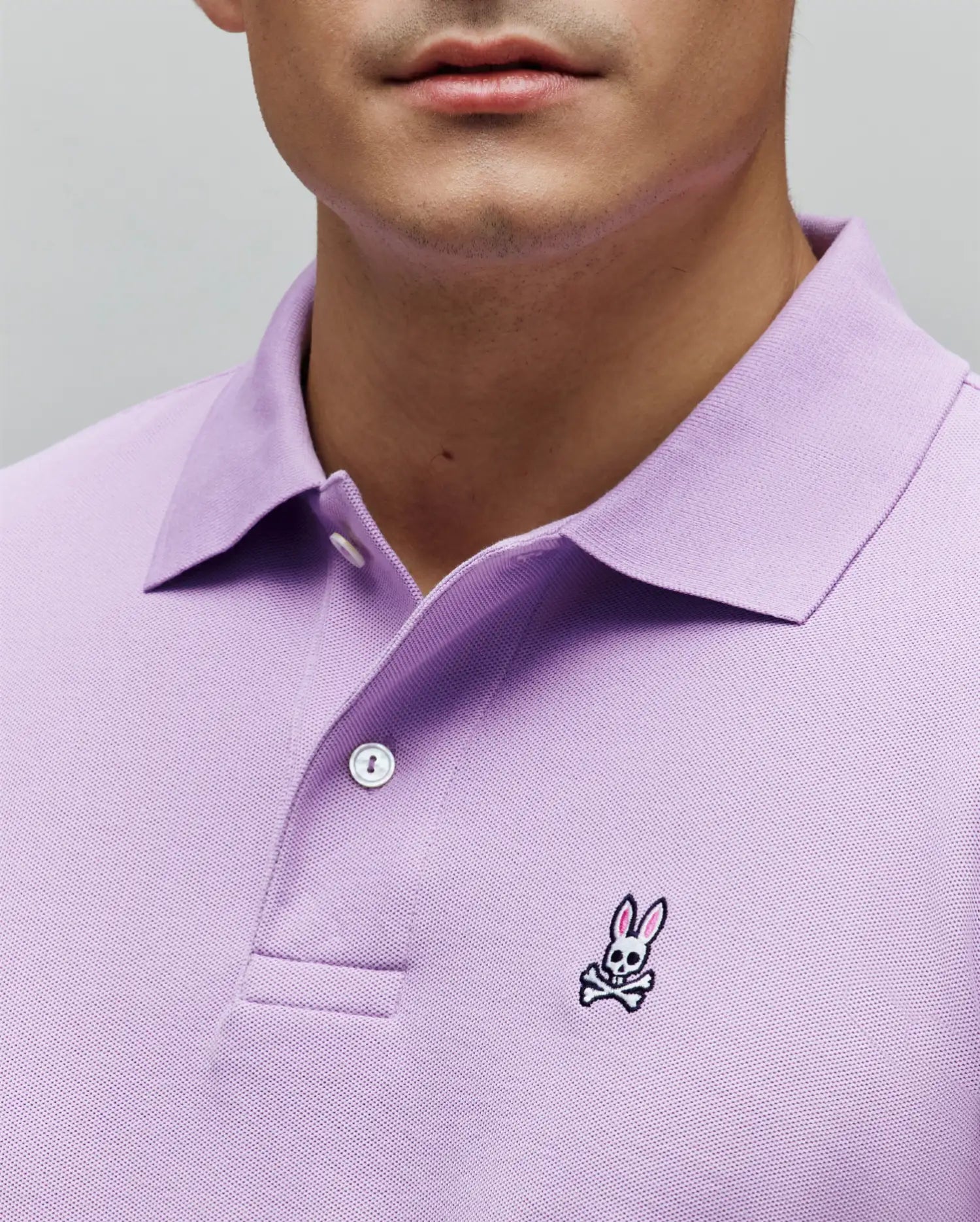 Mens Classic Pique Polo in lavender, featuring a classic fit, two-button placket, and a small embroidered Psycho Bunny skull logo on the left chest with pink ears.