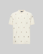 The MENS HOLLAND ALL OVER BUNNY PIQUE POLO (B6K618F200) by Psycho Bunny is a cream short-sleeve polo with a subtle collar and rows of small embroidered bunny logos, shown on a plain grey background.