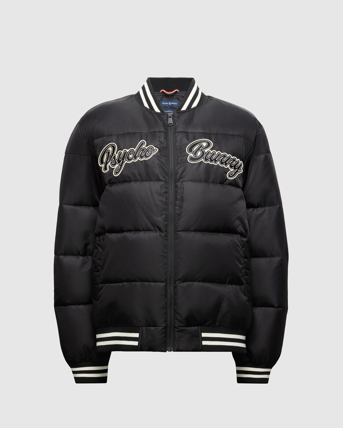 Introducing the MENS FRAZER FASHION PUFFER - B6N338E200 by Psycho Bunny, a sophisticated men's puffer jacket in black. It boasts stylish white striped cuffs and collar, with "Psycho Bunny" embroidered on the front in white for added flair. Its quilted design and convenient front zipper establish it as an essential piece in men's fashion outerwear.