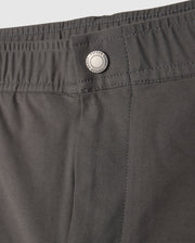 A close-up of the gray MENS MADISON COMMUTER PANT - B6P395Z1WB from Psycho Bunny reveals an elastic waistband and a metal button engraved with "Techwear." The smooth fabric boasts neat stitching and includes a detachable keychain, perfect for the modern commuter.
