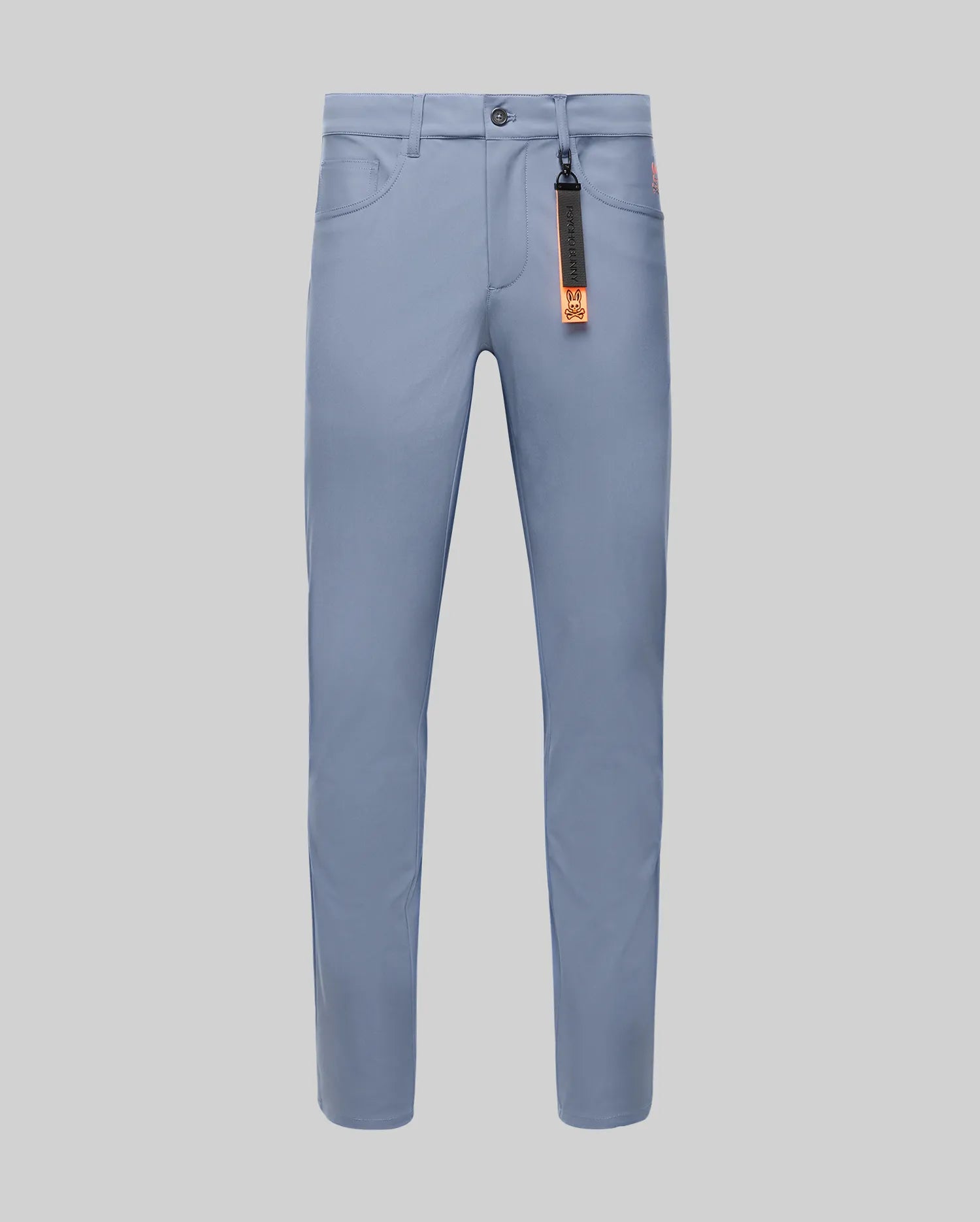 The Psycho Bunny MENS MAVERICK 10K STEP PANT - B6P788D200 is a light blue slim-fit pant with front pockets, belt loops, button closure, four-way stretch, and an orange and black tag on the front right belt loop, shown on a light gray background.