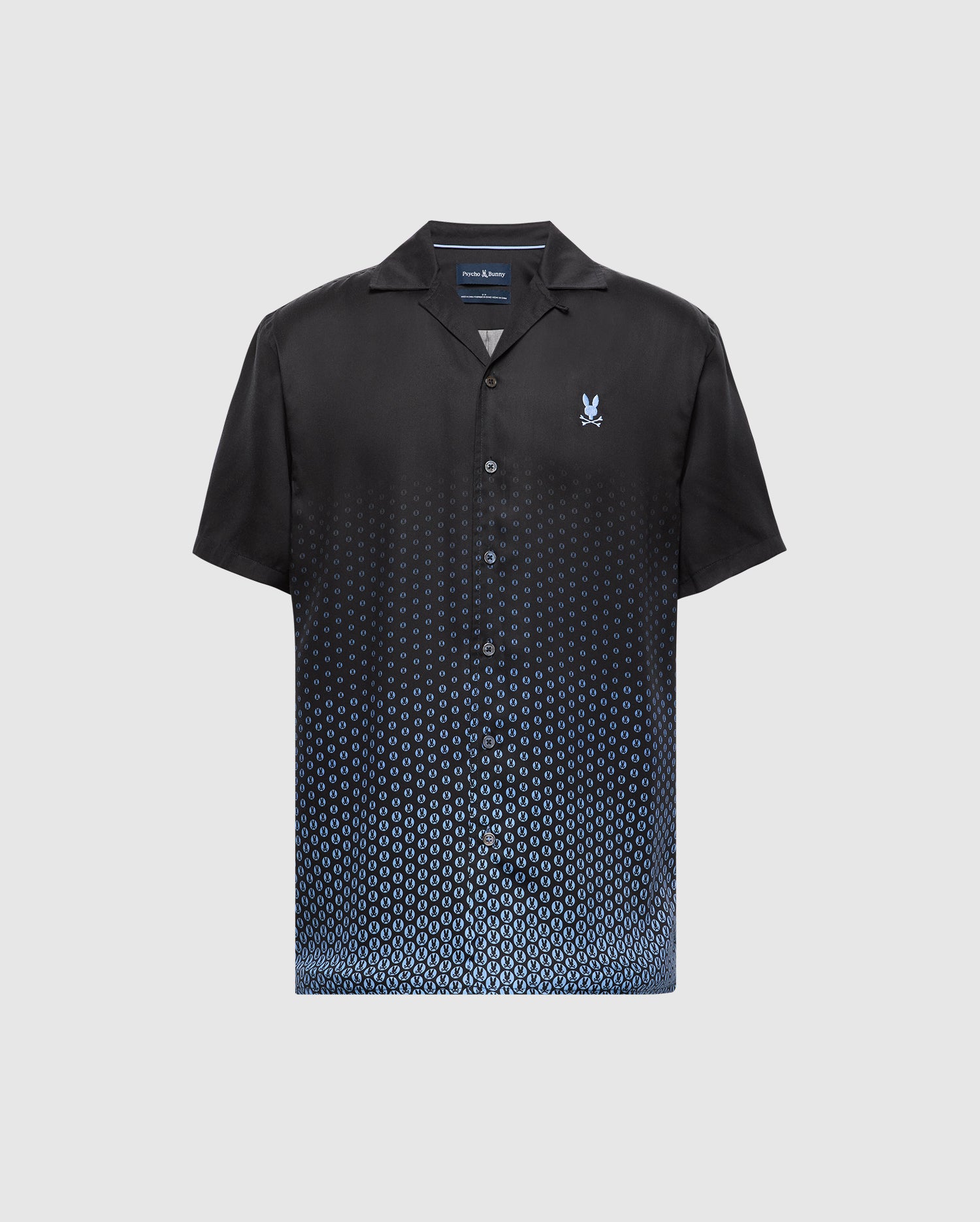 The MENS BENDIGO TENCEL SHIRT - B6Q627F200 by Psycho Bunny is a black short-sleeve shirt with an ombre blue hexagon pattern, made from soft Tencel fabric. It features a camp collar and a small embroidered logo on the chest against a plain white background.