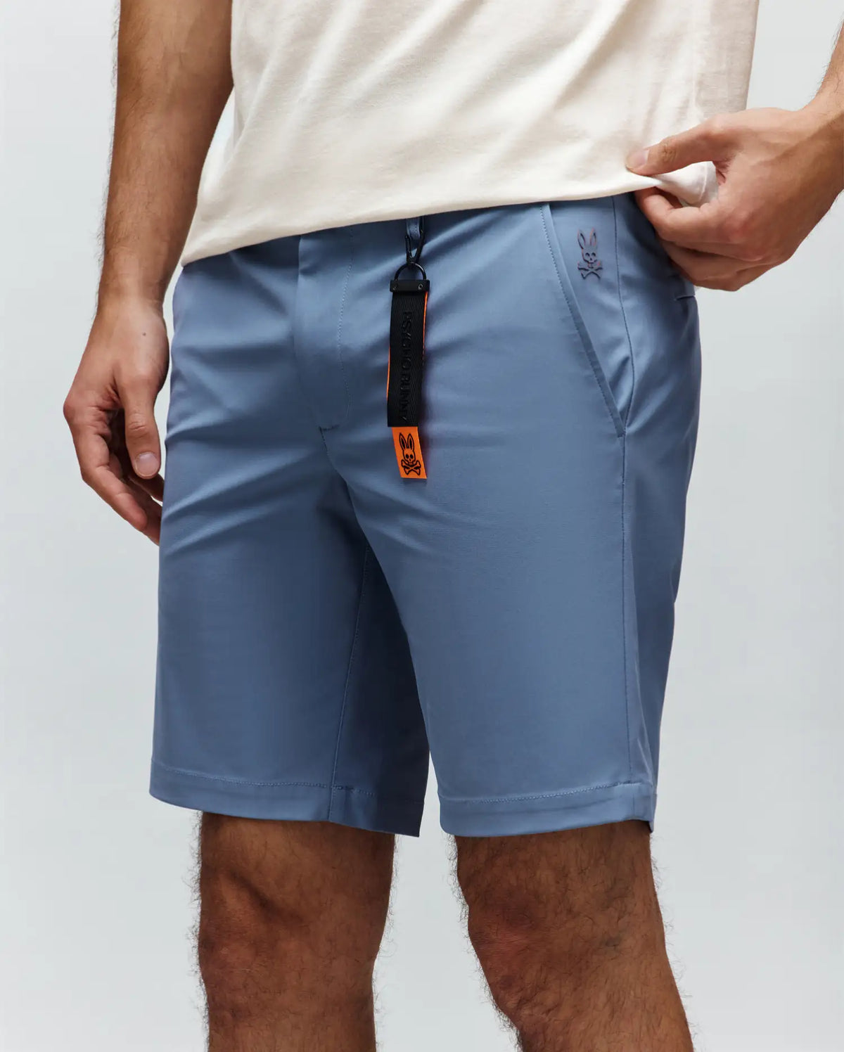 Mens Maverick 10k Step Short in slate blue, crafted from smooth performance fabric with a classic fit, featuring a small embroidered Psycho Bunny skull logo on the right hip and a black and orange branded keychain.