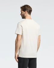 A man with brown hair, facing away from the camera against a plain background, wears a Psycho Bunny MENS CLASSIC CREW NECK TEE - B6U014B200 in vibrant colors, paired with black pants.