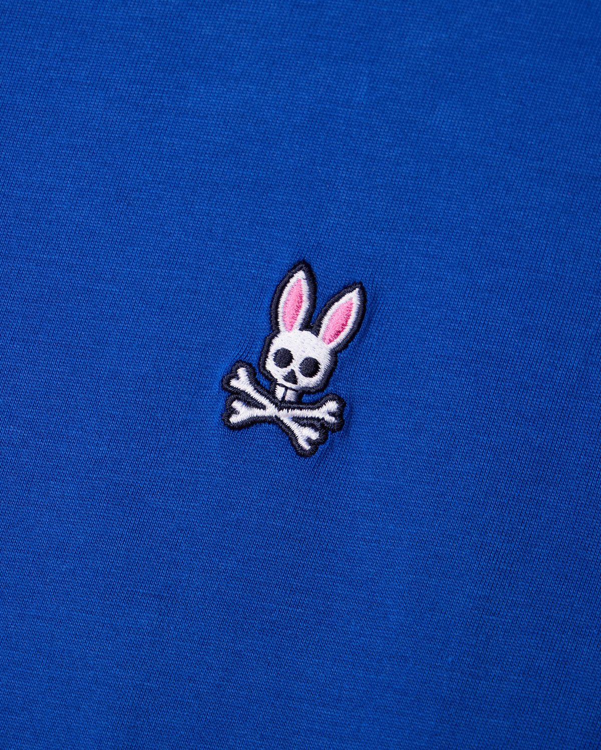 Explore the Psycho Bunny MENS CLASSIC CREW NECK TEE - B6U014CRPC, crafted from premium Pima cotton and adorned with a delightful embroidered cartoon skull design featuring pink rabbit ears above crossed bones.