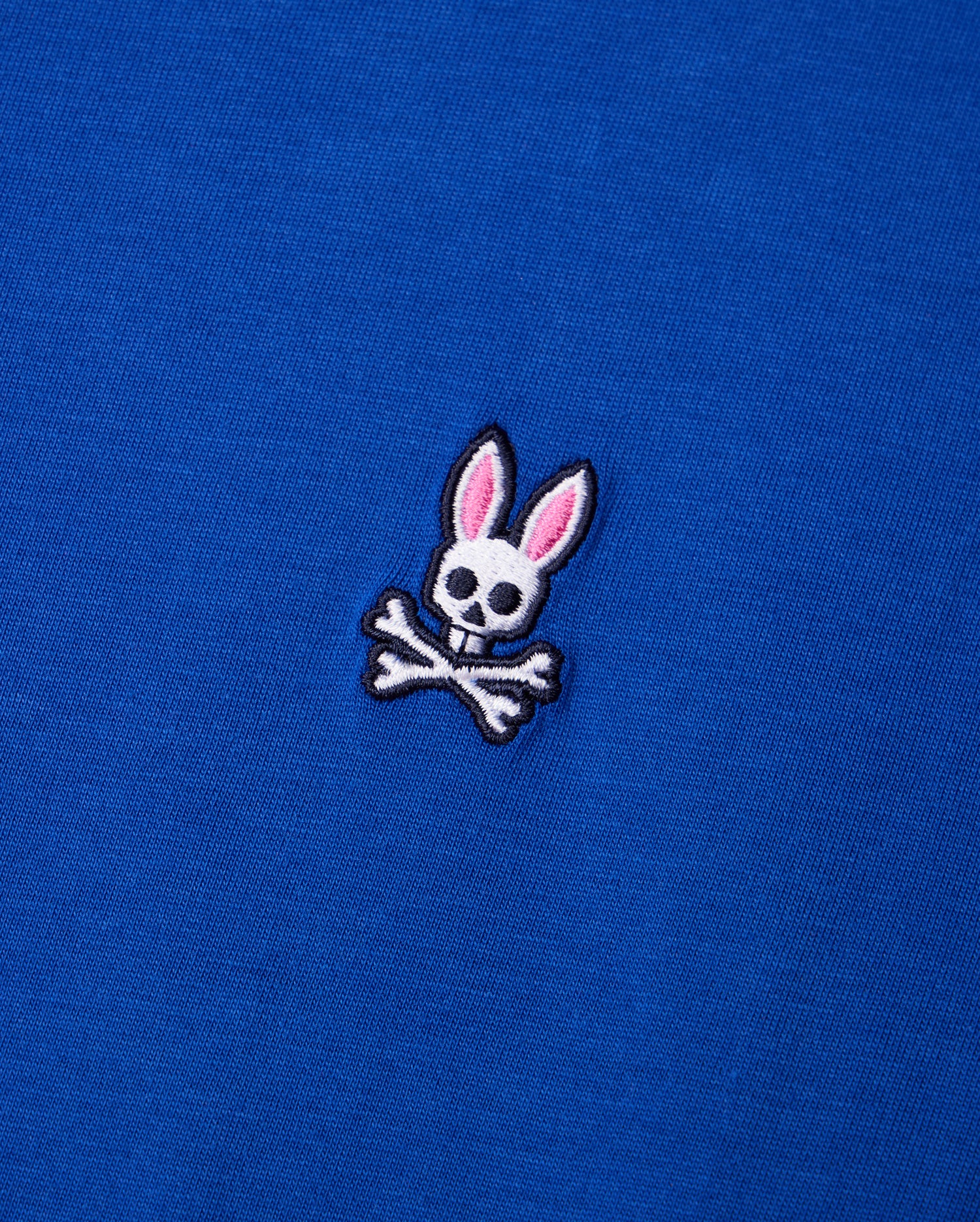 Explore the Psycho Bunny MENS CLASSIC CREW NECK TEE - B6U014CRPC, crafted from premium Pima cotton and adorned with a delightful embroidered cartoon skull design featuring pink rabbit ears above crossed bones.