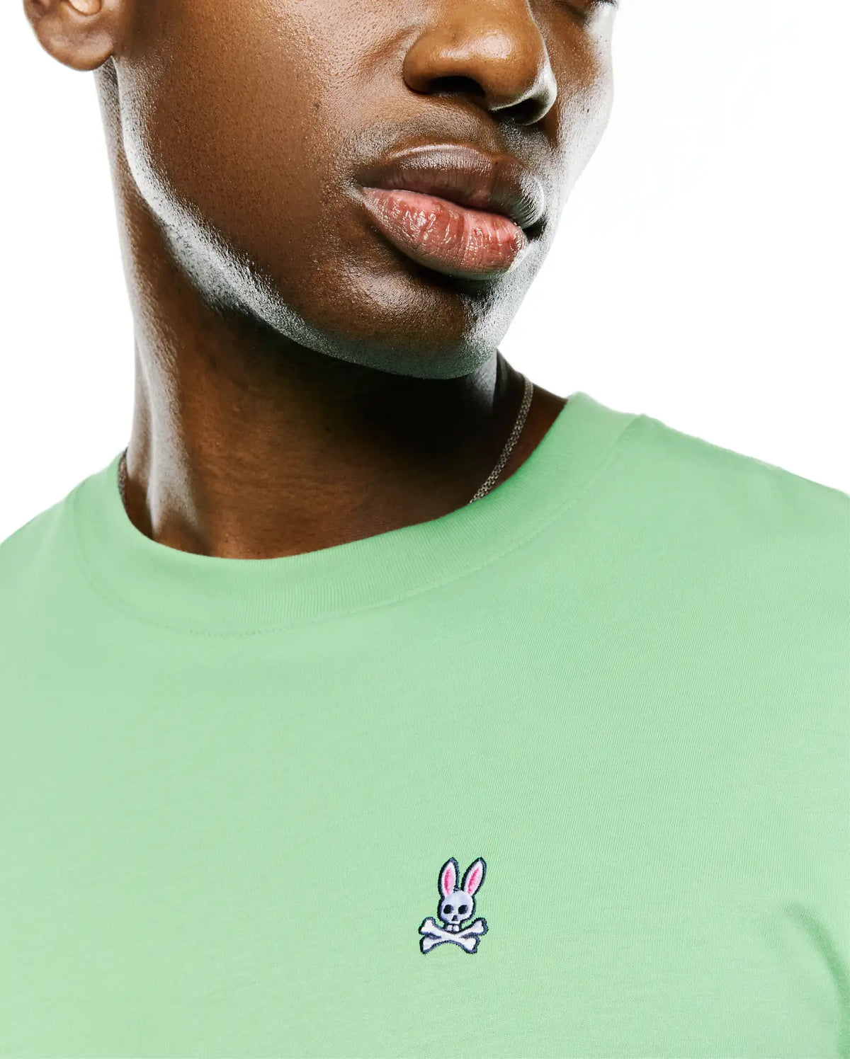 Men's Classic Pima Crew Neck Tee in light green, featuring a smooth jersey texture and a small, embroidered Psycho Bunny skull logo with pink ears on the left chest. (3)