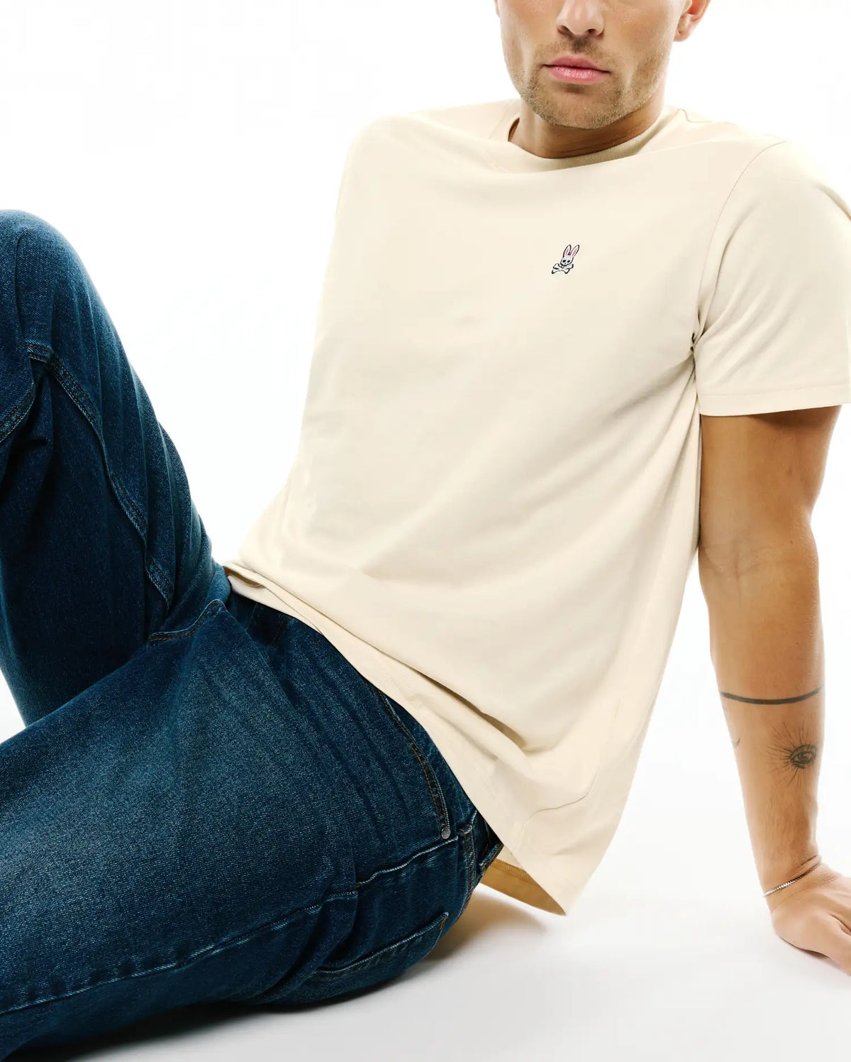 Mens Classic Crew Neck Tee in cream, featuring a classic fit and soft jersey fabric, with a small embroidered pink, blue, and white Psycho Bunny skull logo on the left chest. (3)