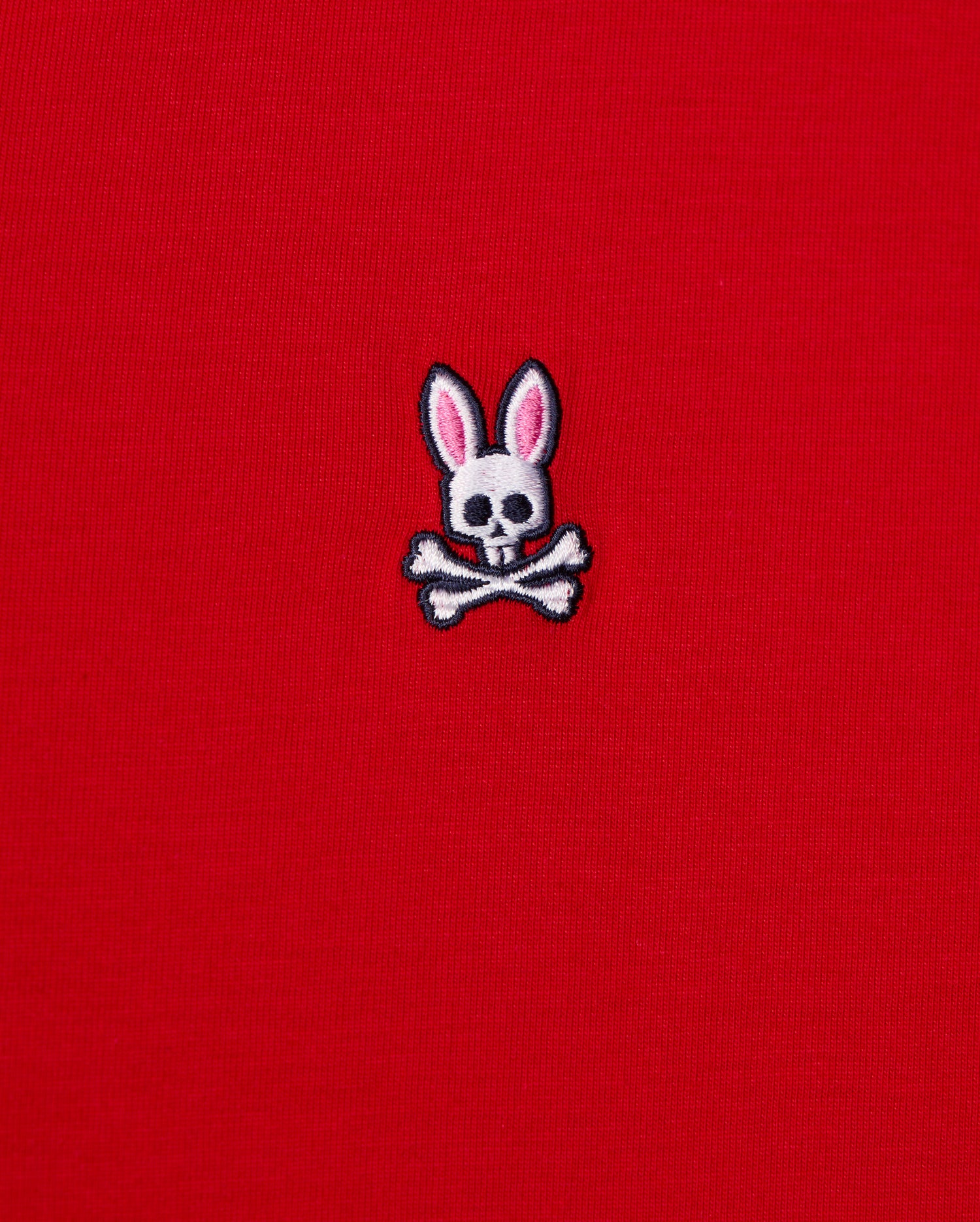 The MENS CLASSIC V NECK TEE - B6U100CRPC from Psycho Bunny showcases a red fabric made of soft Pima cotton and features the brand's signature logo: a white skull and crossbones with playful pink bunny ears.