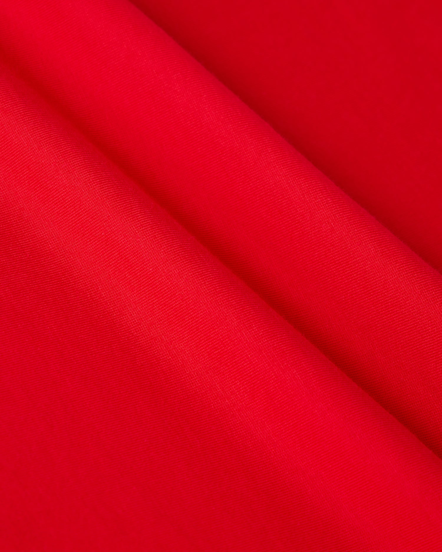 Close-up of the vibrant red Pima cotton fabric from the Psycho Bunny Men's Classic V-Neck Tee - B6U100CRPC, showcasing a smooth and even texture. Slight folds create gentle shadows, highlighting its sheen and refined appearance.