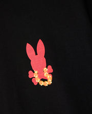Introducing the Psycho Bunny Hawaii City Tee (product code: B6U169Y1PC) for men, a premium Pima cotton T-shirt featuring a black base with an eye-catching pink bunny silhouette and crossbones design, highlighted by a striking yellow floral wreath around its neck. This distinctive piece is perfect for adding a unique flair to any wardrobe.