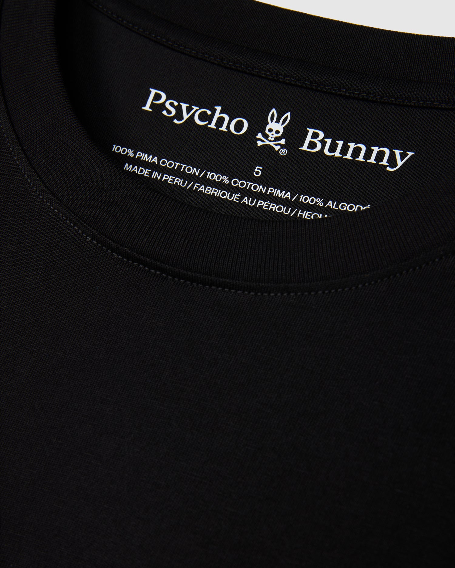 Close-up of the MENS HAWAII CITY TEE by Psycho Bunny, highlighting the black label inside the collar featuring its iconic logo and text indicating it's crafted from 100% Pima cotton, made in Peru.