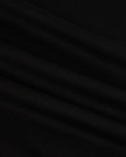 Close-up of the MENS HAWAII CITY TEE - B6U169Y1PC by Psycho Bunny, made from black Pima cotton fabric with a smooth, slightly rippled texture. The dark material displays gentle folds and a subtle sheen, resembling the luxurious quality of a sophisticated men's T-shirt for an elegant appearance.