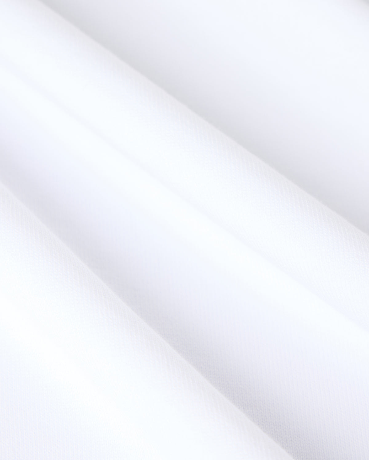 Close-up of heavyweight Pima cotton fabric on the MENS DUKE OVERSIZED TEE - B6U742D200 by Psycho Bunny, showcasing a smooth and clean surface. The solid pattern is evenly textured with subtle diagonal shadows, hinting at soft folds or gentle draping. The overall appearance is crisp, minimalistic, and bright.