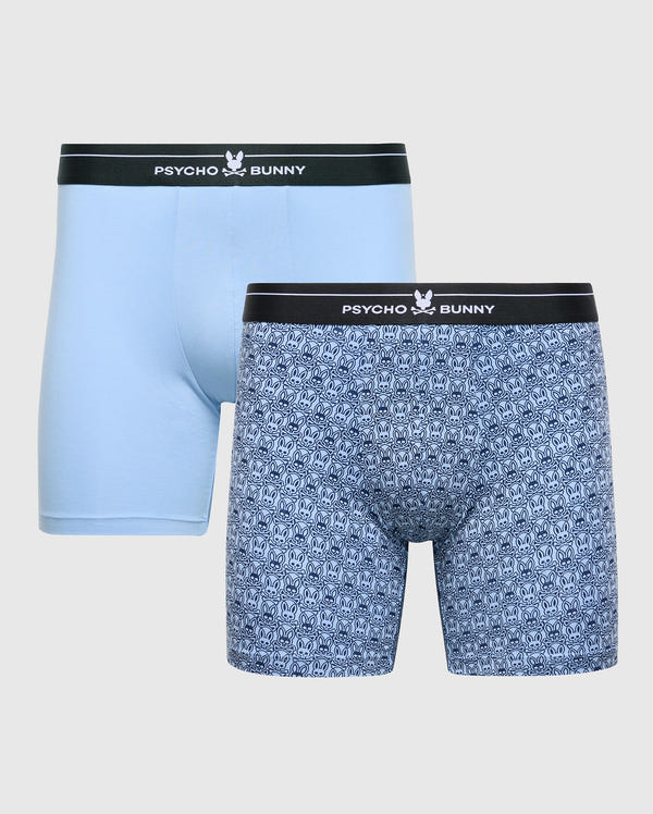 Two pairs of men's boxer briefs from Psycho Bunny's MENS 2 PACK BOXER BRIEF - B6V481F200 set are shown. Made from Stretch Pima cotton, the first pair is light blue, and the second is dark blue with a small pattern. Both have black waistbands featuring "Psycho Bunny" and a white bunny logo for ultimate comfort.