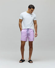 White classic fit jersey t-shirt with small embroidered Psycho Bunny logo on left chest. Mens Samos Hydrochromic Printed Swim Trunk in lavender, with dark blue drawstring and small embroidered logo.